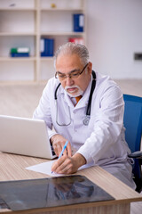 Old male doctor working in the clinic