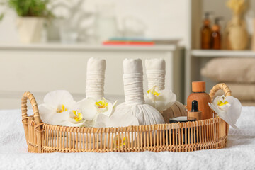 Fototapeta na wymiar Wicker tray with herbal bags and other spa products on white bath towel