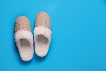 Pair of beautiful soft slippers on light blue background, top view. Space for text