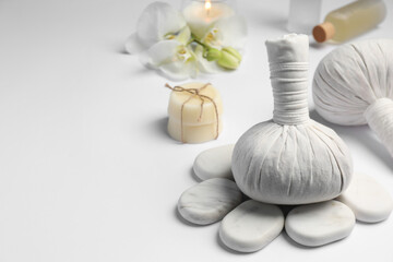 Herbal massage bags and other spa products on white table, space for text