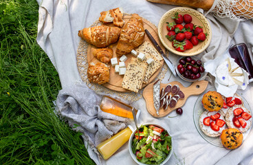 Picnic in the field with berries, juice, cheese, sausage and sweet croissants