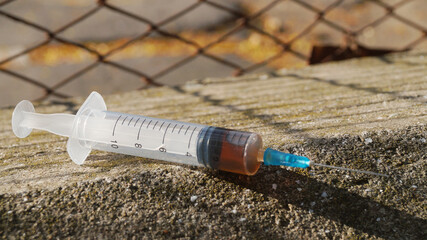 Syringe with hard drugs on stone surface outdoors, closeup