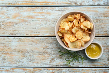Tasty homemade parsnip chips with sauce and rosemary on old light blue wooden table, flat lay. Space for text