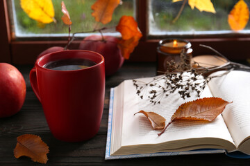 Naklejka na ściany i meble Book with dried flower as bookmark and cup of hot drink on wooden table