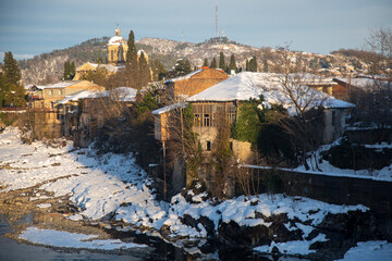 Old part of Kutaisi with houses and churches covered with snow over the river, Georgia