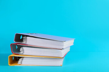 Stack of office folders on light blue background, space for text