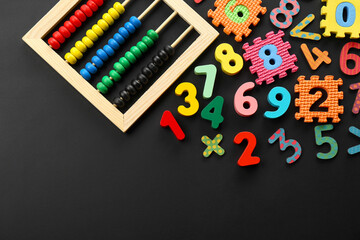 Many colorful numbers and mathematical symbols near abacus on black background, flat lay. Space for...