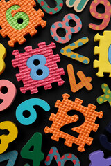 Many colorful numbers and mathematical symbols on black background, flat lay