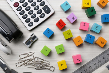 Colorful cubes with numbers and stationery on white wooden table, flat lay