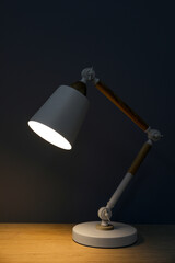 Stylish modern desk lamp on wooden table at night