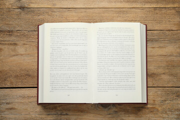 Open book on wooden table, top view