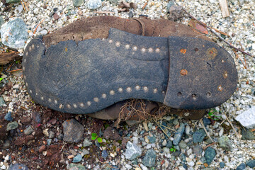An old torn thrown shoe lies on the ground close-up.