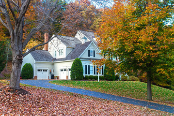 Suburban House among autumn trees. Large manicured lawn and landscaping.