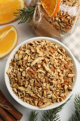 Bowl of dried orange zest seasoning, fresh fruit and cinnamon on white marble table, flat lay