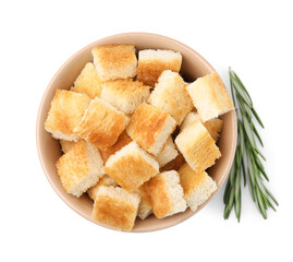 Delicious crispy croutons in bowl and rosemary on white background, top view