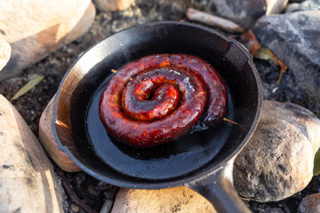 Sausage on the pan over an open fire. Preparing food in nature.