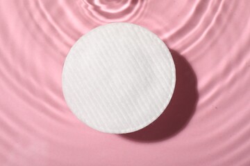 Cotton pad and micellar water on pink background, top view © New Africa