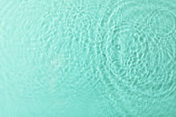 Fototapeta na wymiar Clear water with rippled surface on turquoise background, top view