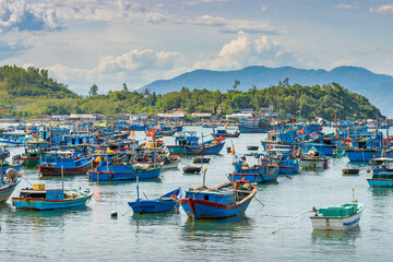 Fototapeta na wymiar A small bay with many brightly painted fishing boats and mountains behind at Vihn Luong in Vietnam