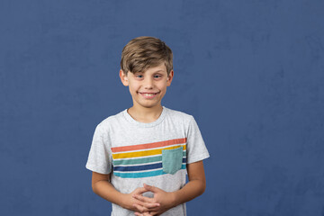 a cute autistic elementary school boy on a blue background with copy space - obrazy, fototapety, plakaty