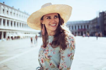 happy trendy woman in floral dress with hat sightseeing