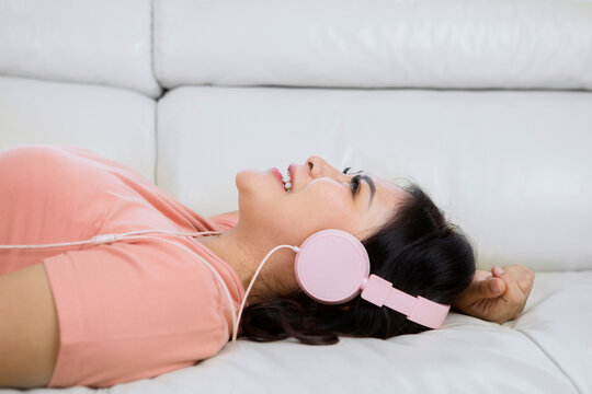 Happy woman enjoying music with headphone on sofa