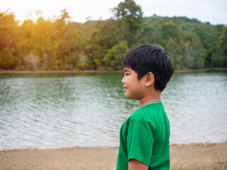 Fototapeta na wymiar A boy stands by the reservoir in the evening. It shows looking at the goals in life.