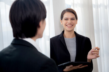 Young manager talking with secretary about report marketing on digital tablet for planning at office, executive discussion with employee woman together, leadership and employee, business concept.