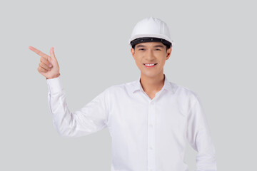 Portrait young asian man is engineer wearing helmet standing and smiling with confident isolated white background, male is architect or contractor presenting or showing something, industrial concept.