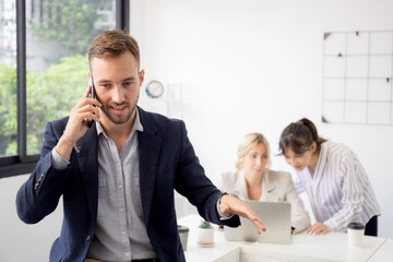 Portrait of young businessman smiling and talking smartphone with satisfied while employee or colleagues working at office, manager or executive using smart phone, business and communication concept.
