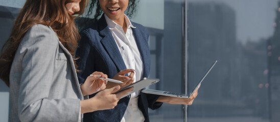 Fototapeta premium Two asia business women in conversation walking together on city street. Corporate colleagues workmate discussing new project while going to work. business outdoor.