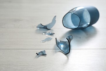 Broken blue glass vase on wooden floor, closeup