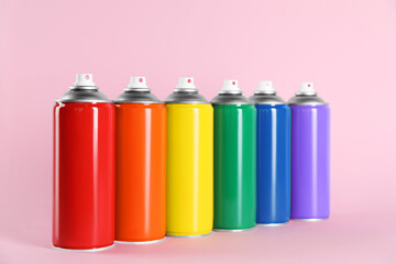 Colorful cans of spray paints on pink background