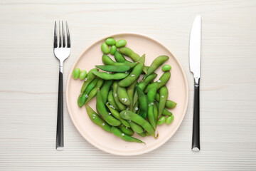 Green edamame beans in pods served on white wooden table, flat lay