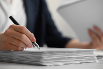Woman signing documents at white wooden table in office, closeup. Space for text
