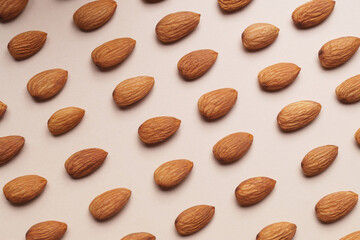 Delicious raw almonds on beige background, flat lay