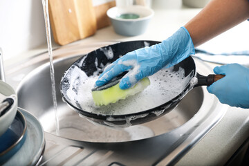 Woman washing dirty frying pan in sink indoors, closeup - Powered by Adobe