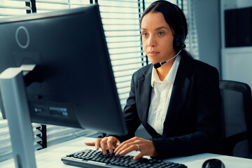 Competent female operator working on computer and talking with clients. Concept relevant to both call centers and customer service offices.