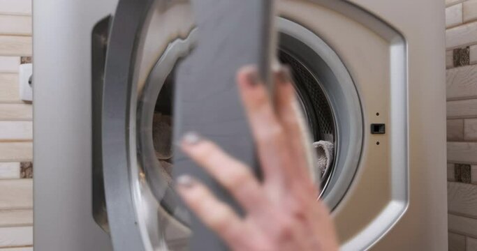 Washing machine close up, Female hand opens and unloads clean laundry . Routine household chores. Laundered terry towels