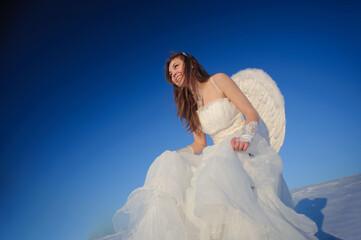Fototapeta na wymiar Beautiful young woman in wedding dress walking on snow field