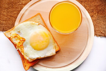 beautiful breakfast in the morning. bread toasts fried to crisp with scrambled egg and bright orange juice in glass on wooden plate. Top view, flat lay