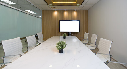 Conference room in a modern office building. Marble table, chair and large presentation monitor with blank screen prepare for a team meeting.