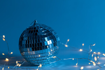 Disco ball and garland on blue background, concept of Christmas and parties, copy space.
