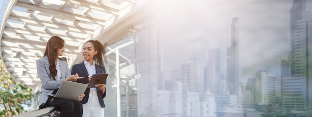 Two asia business women in conversation walking together on city street. Corporate colleagues workmate discussing new project while going to work. business outdoor.