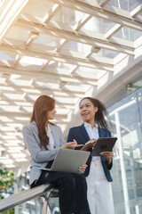 Two asia business women in conversation walking together on city street. Corporate colleagues workmate discussing new project while going to work. business outdoor.