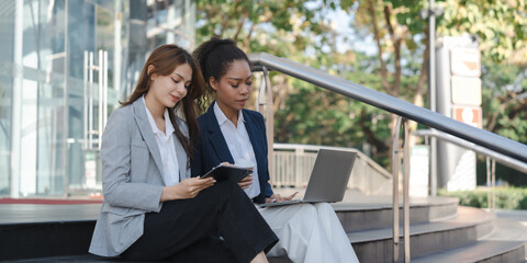 Two asia business women in conversation walking together on city street. Corporate colleagues workmate discussing new project while going to work. business outdoor.