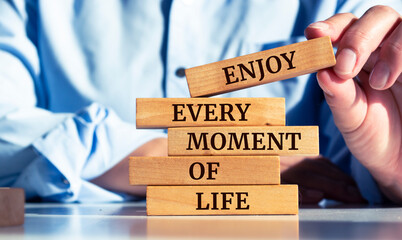 Closeup on businessman holding a wooden block with "Enjoy every moment of life" message