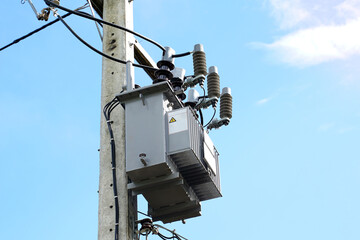 Power transformer installed on electric pole on daytime sky background. Soft and selective focus.  ...