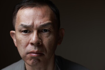 Middle-aged Japanese man in gray casual shirt on gray background. Conceptual image of world peace, stability in daily life, and sustainable living.