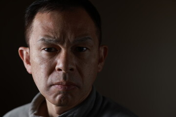 Middle-aged Japanese man in gray casual shirt on gray background. Conceptual image of world peace, stability in daily life, and sustainable living.